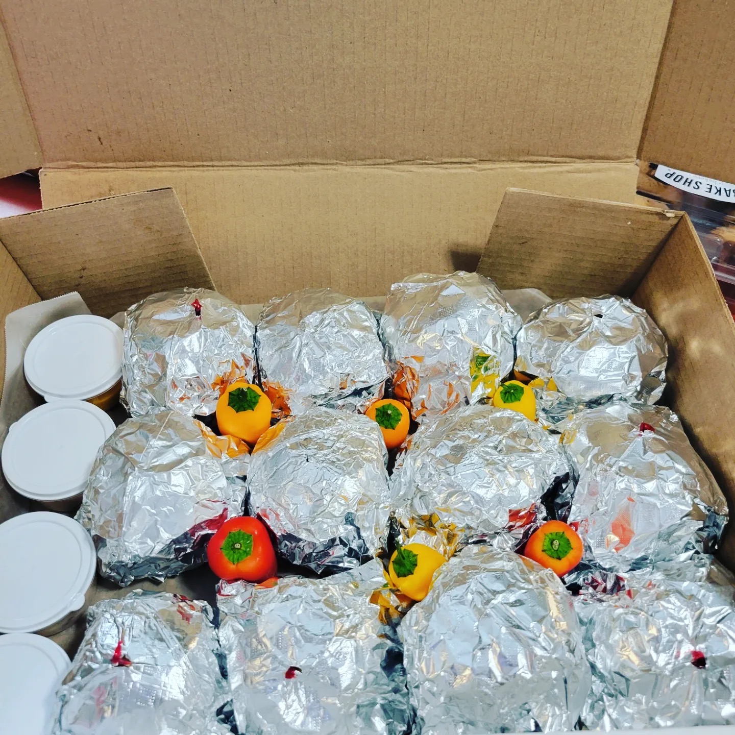 Box of individually wrapped catered lunches garnished with mini sweet peppers